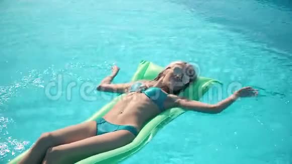 躺在游泳池充气床垫上的年轻漂亮女人视频的预览图