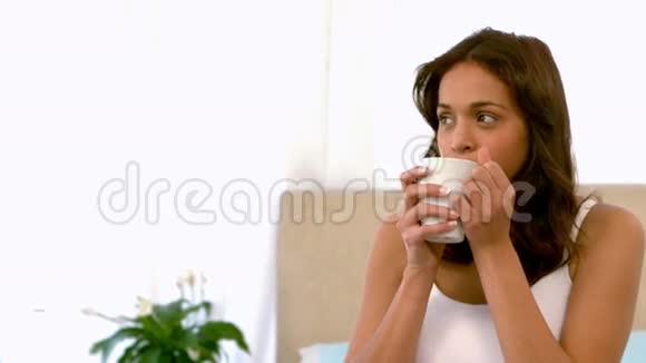 快乐的女人在床上喝茶视频的预览图
