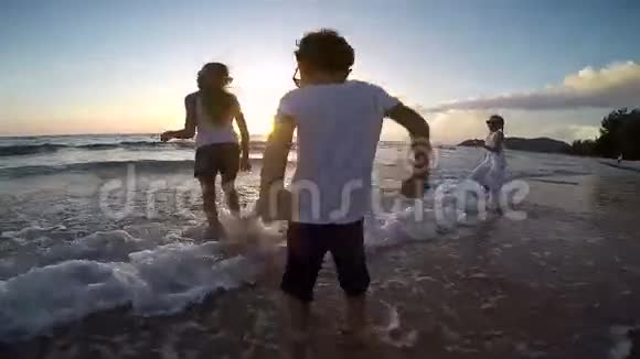 快乐的孩子们在日落时在海滩上玩耍视频的预览图