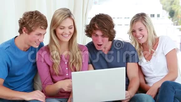 快乐的朋友们一边笑着看着笔记本电脑视频的预览图