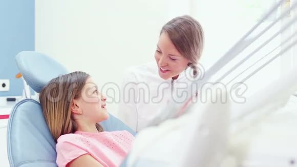 女牙医和小女孩在牙椅上聊天视频的预览图