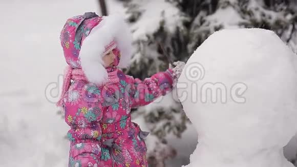 女孩在冬天的雪地里雕刻雪人视频的预览图