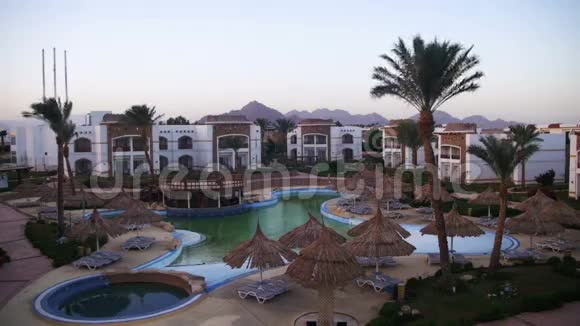 有蓝色游泳池棕榈树和日光浴床的酒店度假村视频的预览图