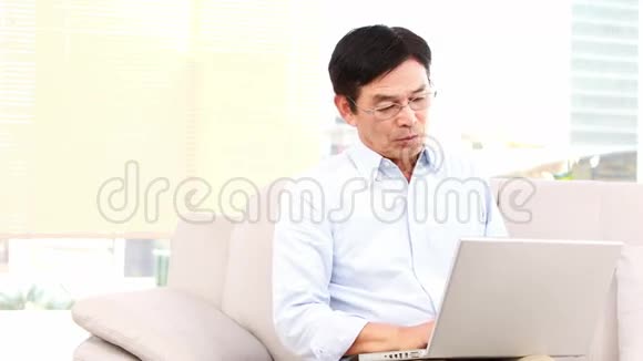 在沙发上用笔记本电脑的亚洲人视频的预览图