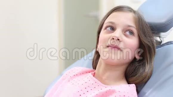 小女孩坐在牙科椅上微笑着说话视频的预览图