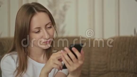 年轻漂亮的女人在家里用智能手机视频的预览图