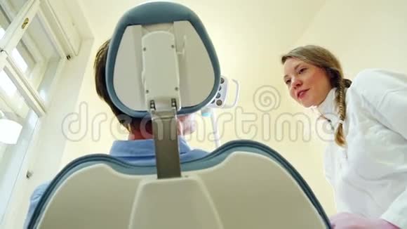 友好的女牙医与病人交谈视频的预览图