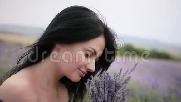 年轻美丽的黑发女人在薰衣草的田野里散步跳舞视频的预览图