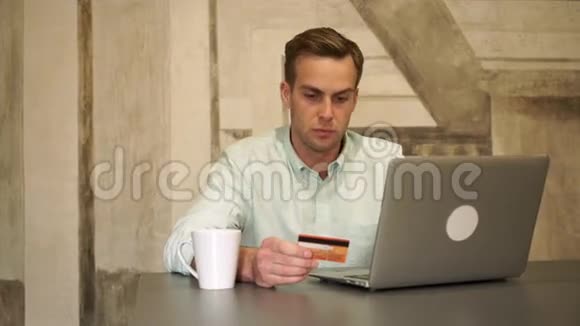 年轻英俊的男人用电脑和信用卡买东西视频的预览图