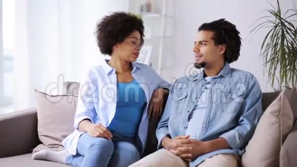 快乐的一对夫妇坐在沙发上在家里聊天视频的预览图
