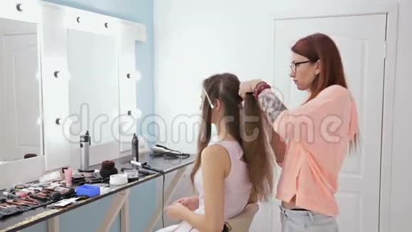 为留长发的年轻美女做发型的专业理发师视频的预览图