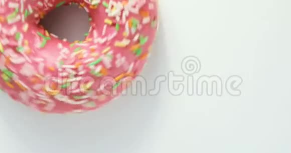 明亮多彩的撒着甜甜圈的特写镜头在白色背景上旋转美味甜甜圈旋转视频的预览图
