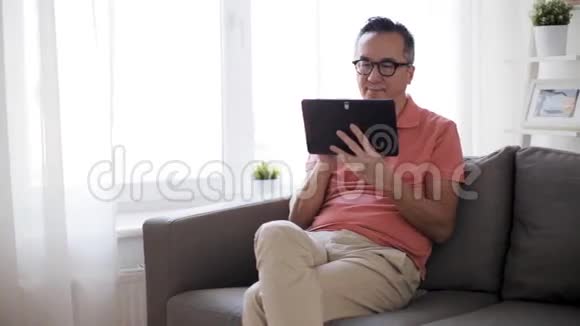 有平板电脑的男人坐在家里的沙发上视频的预览图