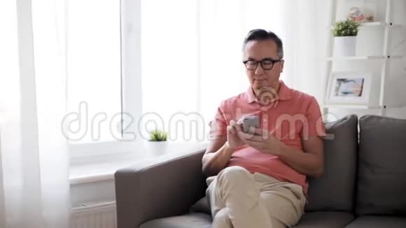 有智能手机的男人坐在家里的沙发上视频的预览图