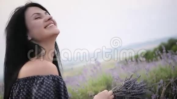 年轻美丽的黑发女人在薰衣草的田野里散步跳舞视频的预览图