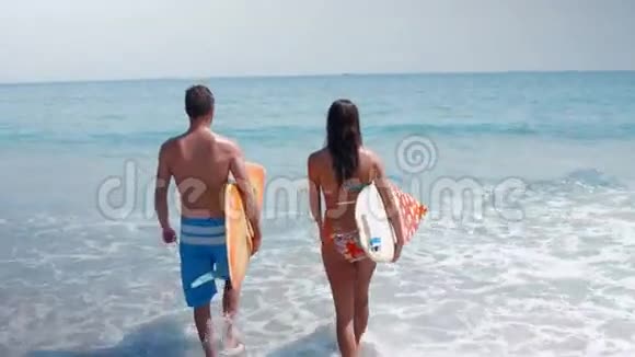 两名冲浪者带着冲浪板在海上行走视频的预览图