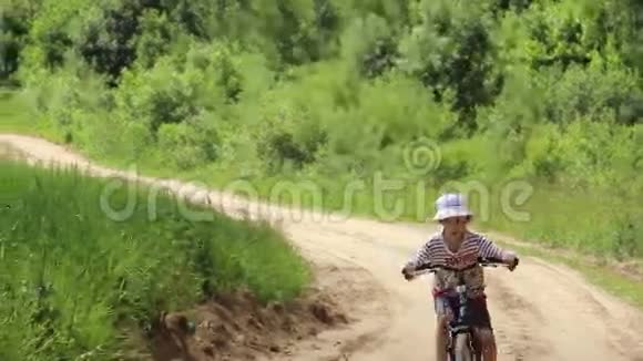 一个男孩骑着自行车在农场的沙路上视频的预览图