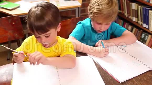 可爱的小学生在图书馆写作视频的预览图