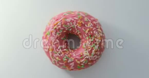 明亮多彩的撒着甜甜圈的特写镜头在白色背景上旋转美味甜甜圈旋转视频的预览图