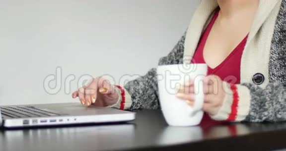 女人一边喝咖啡一边用笔记本电脑视频的预览图