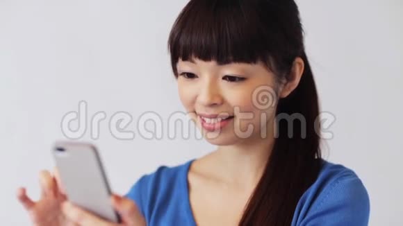带着智能手机的快乐微笑的亚洲女人视频的预览图