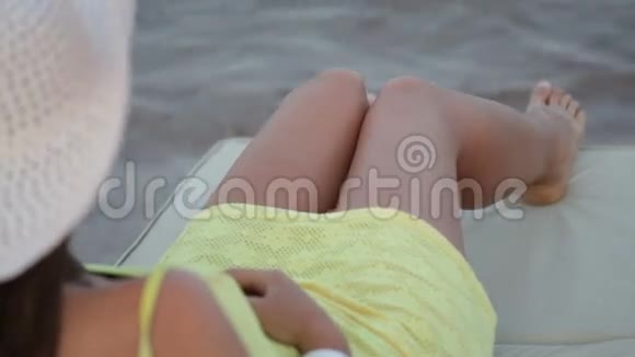 在海滩上戴帽子日光浴卧室的漂亮女人视频的预览图