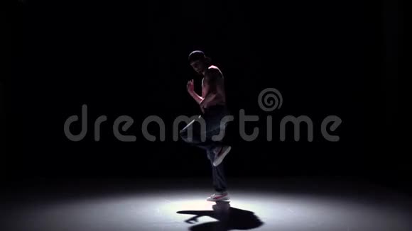 戴着帽子的男子在黑色阴影慢动作上跳舞视频的预览图