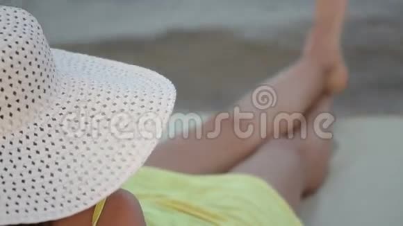 在海滩上戴帽子日光浴卧室的漂亮女人视频的预览图