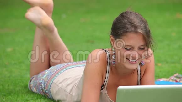 在草地上玩手提电脑的漂亮学生视频的预览图