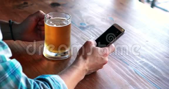 男人喝啤酒时用手机视频的预览图
