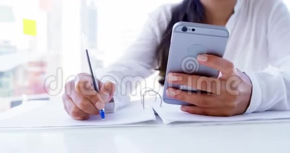 女人用智能手机做笔记视频的预览图