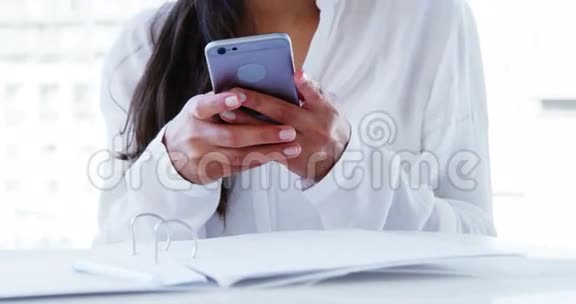 微笑的女人在办公室里用智能手机视频的预览图