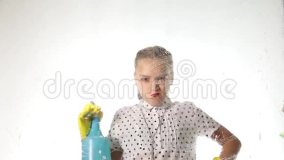 微笑的小家庭主妇用喷雾布和洗涤剂洗窗户泡沫中的大玻璃家庭工作概念视频的预览图