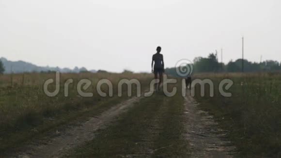 有狗的年轻女人在田里散步的女孩视频的预览图