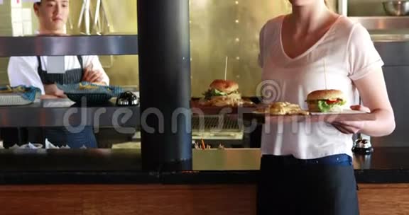 餐厅里拿着汉堡和炸薯条的女人视频的预览图