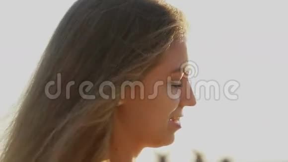 海滩上的女孩日落时分她的头发随风飘动视频的预览图