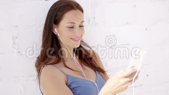有魅力的女人用耳机听音乐视频的预览图
