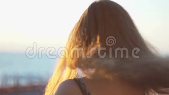 海滩上的女孩日落时分她的头发随风飘动视频的预览图
