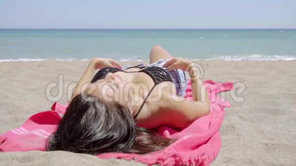 年轻女子在热带海滩晒日光浴视频的预览图