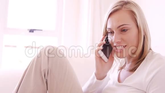 金发女人坐在沙发上打电话视频的预览图