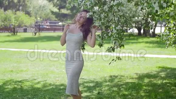 年轻女子在树的背景下享受视频的预览图