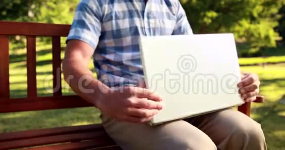 坐在公园长椅上的人用笔记本电脑视频的预览图