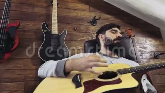 英俊的胡子男人弹吉他慢动作视频的预览图