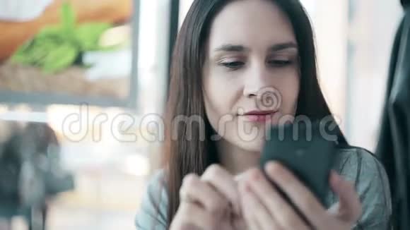 漂亮的女人在咖啡馆里使用智能手机视频的预览图
