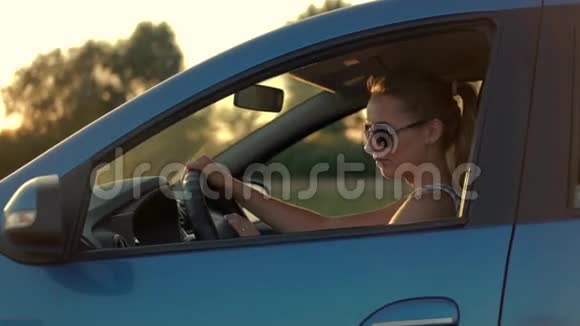 美丽的年轻女子坐在车里驶入夕阳视频的预览图