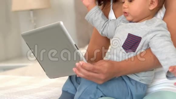妈妈带着她可爱的宝宝用数码平板电脑视频的预览图