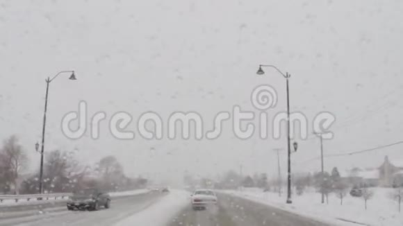 在寒冷的冬季暴风雪中驾驶汽车行驶在道路上视频的预览图
