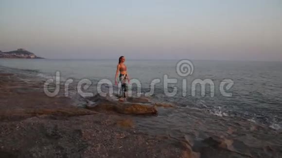 日落时分年轻女子在海滩上练习瑜伽视频的预览图