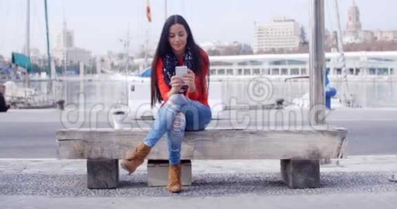 城里坐在长凳上的年轻女子视频的预览图