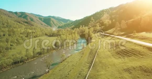 在阳光明媚的夏日早晨空中飞过新鲜的山河和草地农村土路下面视频的预览图